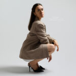 Frau in braunem Blazer kauert